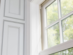 White paneled wall and a window with light streaming through; green trees visible outside, creating a serene and bright atmosphere.