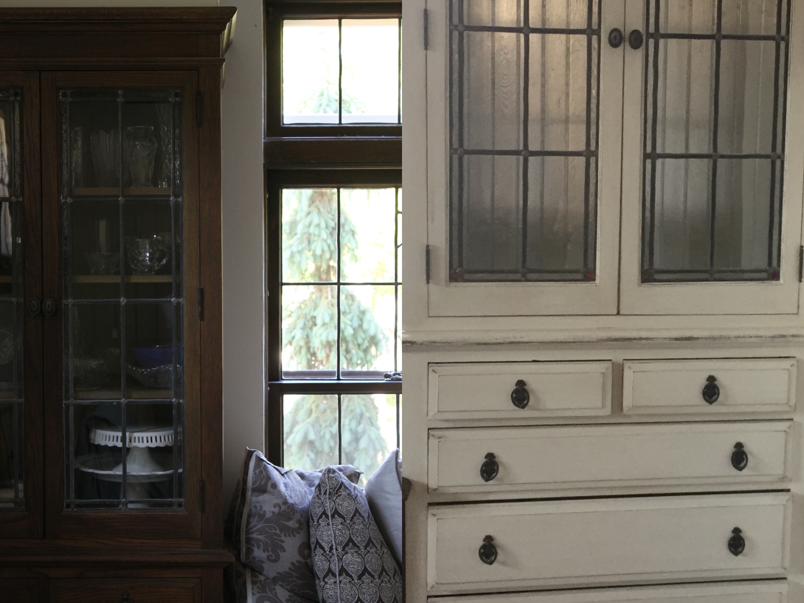 Wooden and white cabinets with glass doors, decorative pillows below, and a tree visible through the window, creating a cozy, rustic vibe.