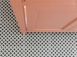 Black and white patterned tile floor and the lower part of a peach-colored cabinet, creating a stylish, geometric design.