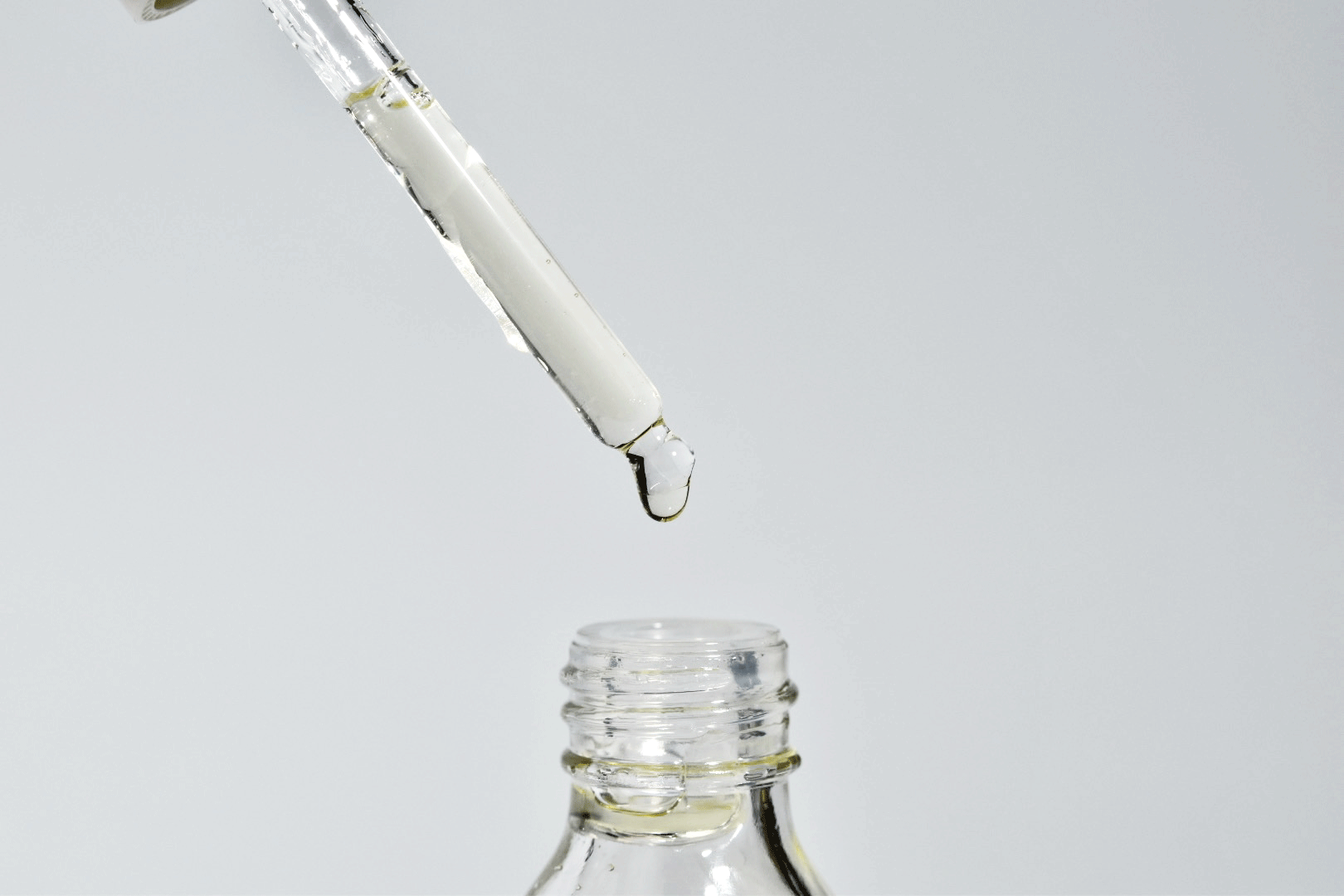 Dropper releasing COSRX snail mucin into a glass bottle.