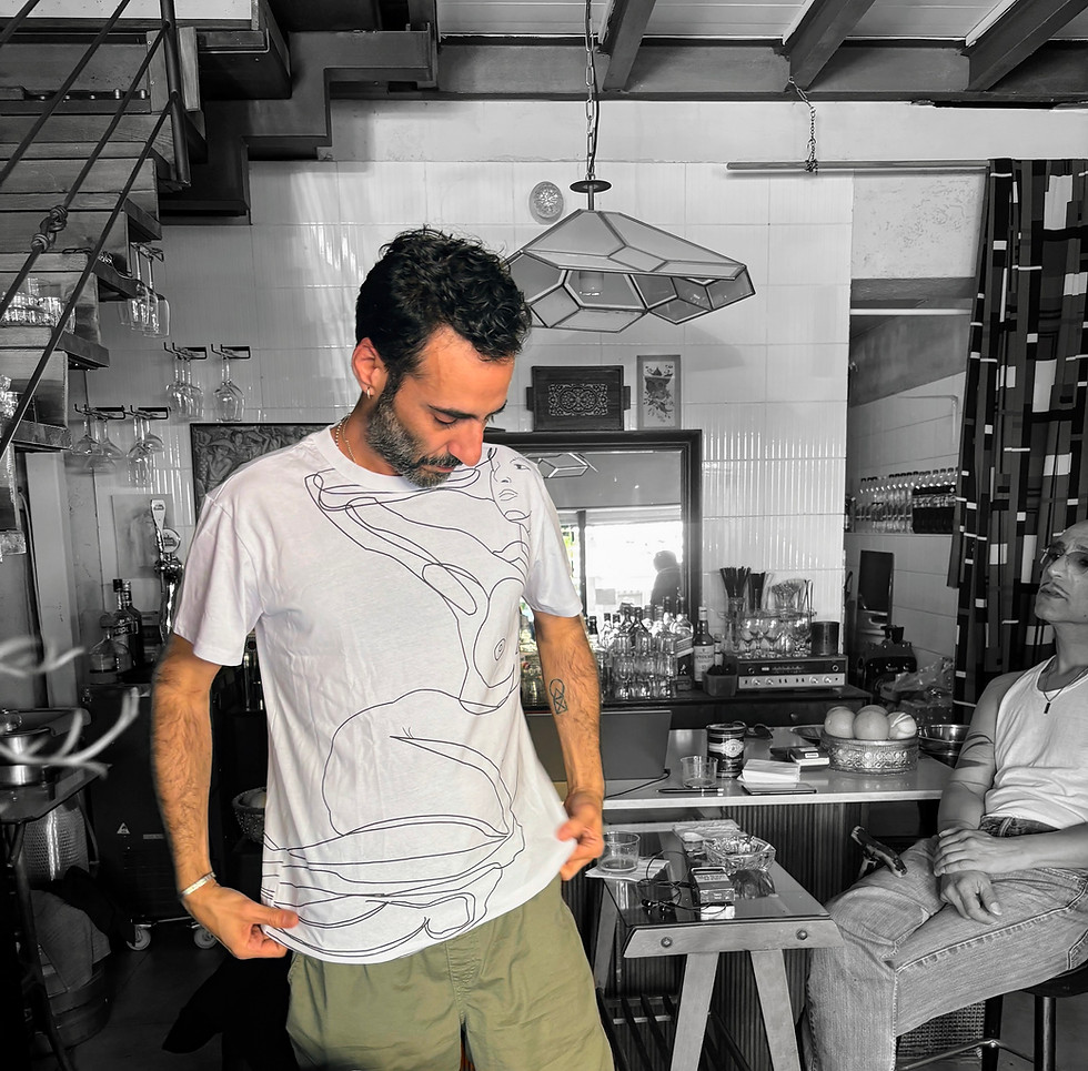 an Arab model looking down at the shirt his wearing inside a bar