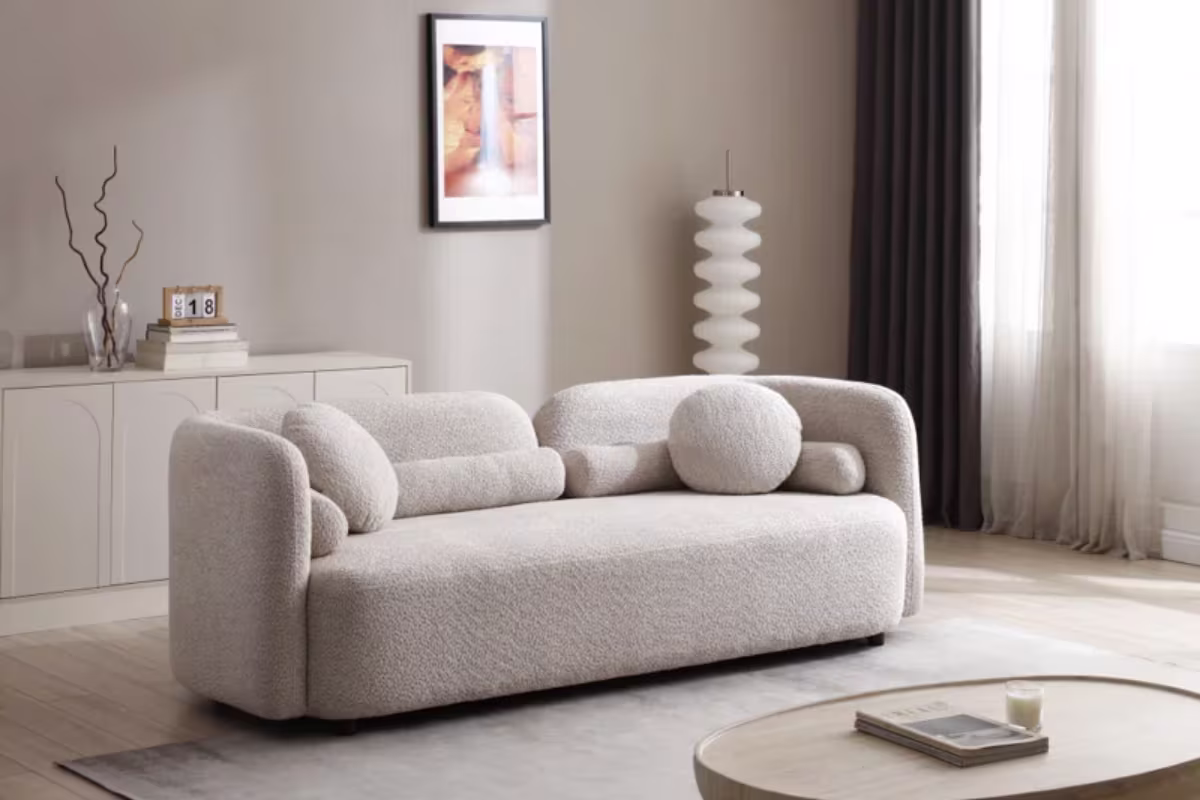 Beige textured fabric sofa from Wayfair with round cushions and cylindrical bolsters places in a living room with taupe paint color
