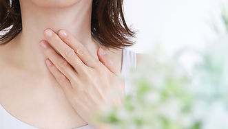 のどに手をあてる女性