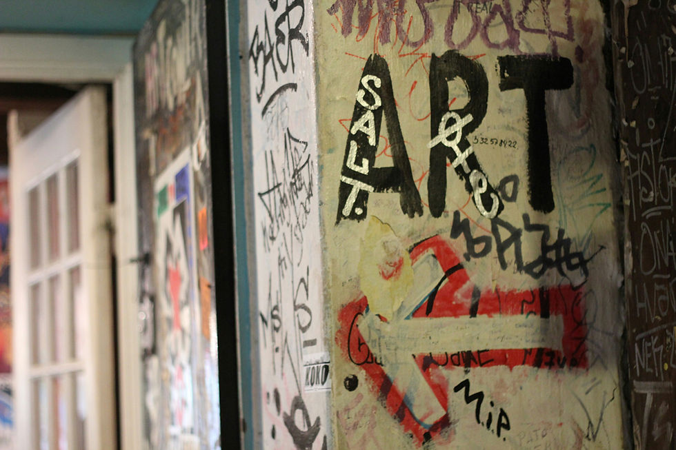 Graffitied wall with bold text "ART," surrounded by scribbles and tags. Open door in the background, creating an urban, edgy vibe.
