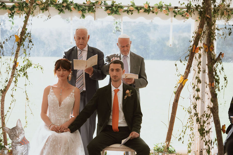Two male relatives stand behind bride and groom during a modern wedding ceremony. They place their hands on the couple's heads while bestowing a blessing on them. Part of a modern Jewish wedding ceremony by Beth Kirkham ceremonies, trusted sussex celebrant