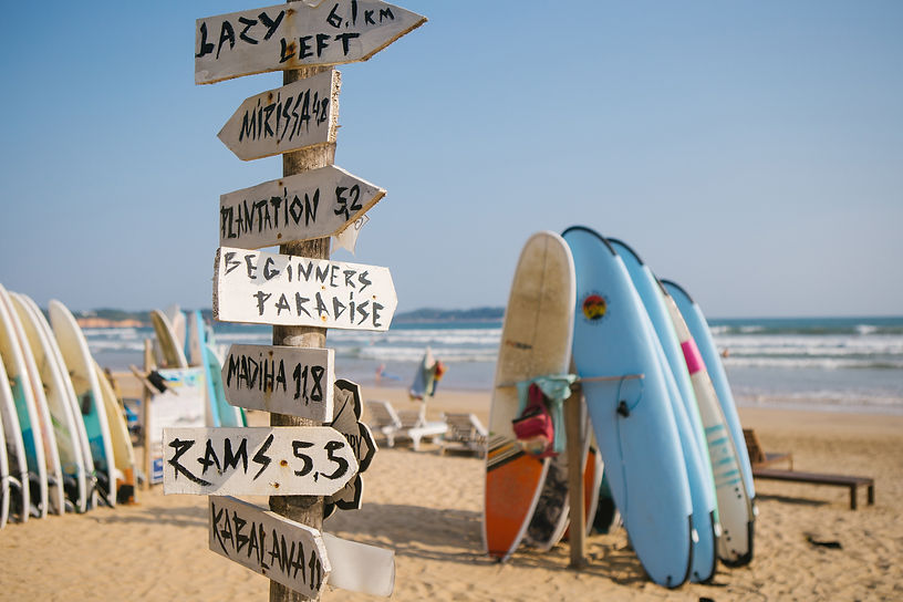 surf boards standing up on the beach with signs pointing in every direction.jpg