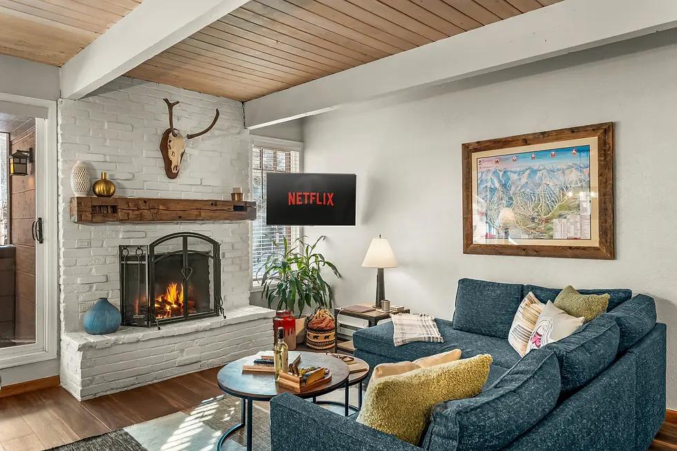 Modern mountain lodge living room with fireplace at Breckenridge summer vacation rental, featuring white brick, wooden