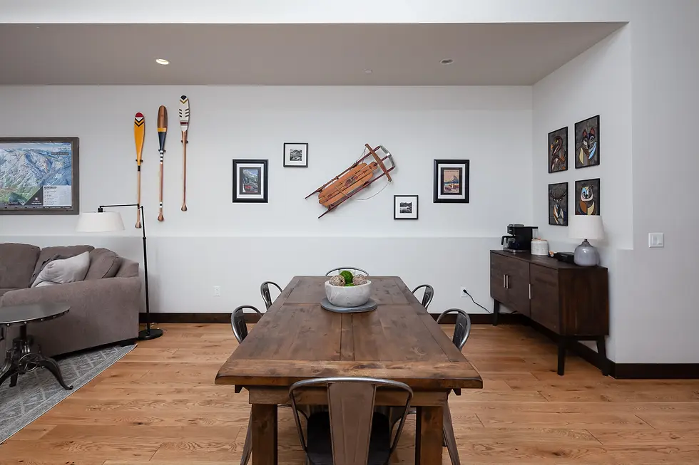 Rustic lodge living room with wooden dining table, vintage mountaineering decor, and hardwood floors near Glacier National
