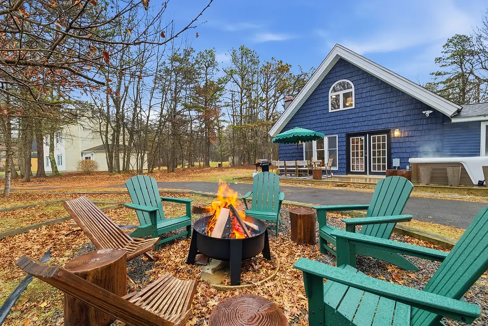 Blue Tail Chalet fire pit with turquoise Adirondack chairs and active flame in Pocono Mountains backyard at dusk