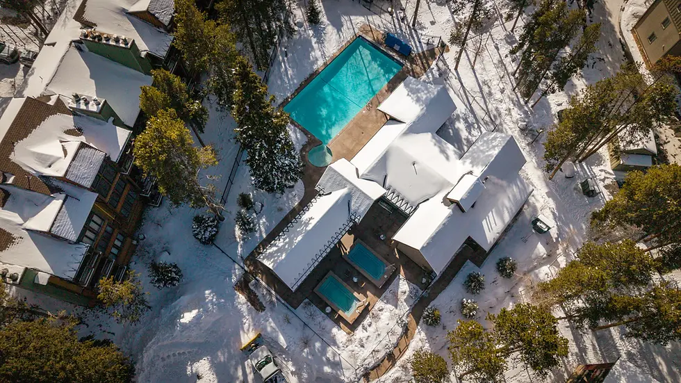 Aerial view of heated pools at luxury Breckenridge CO winter property surrounded by snow and evergreens