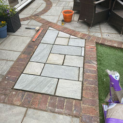 Filling in a section of flower bed within an existing patio area with matching patio tiles in Hove.