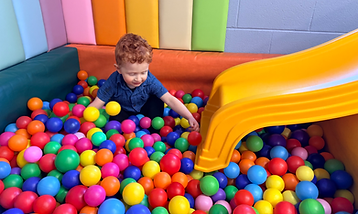 Young boy playing in a ball pit with slide