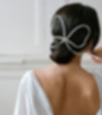 Brunette bride wears hair in a low bun accessorised with an extra large crystal bow set on a silver comb