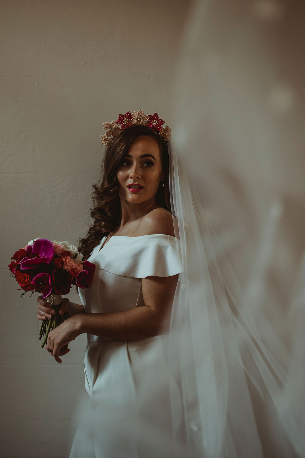 Bride wears pink beaded flower crown and veil and holds a pink bouquet