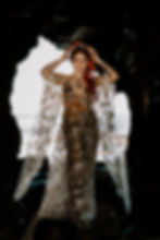 Bride stands in the mouth of a cave wearing a gold overlay celestial themed wedding dress and a gold stars and moons crown.
