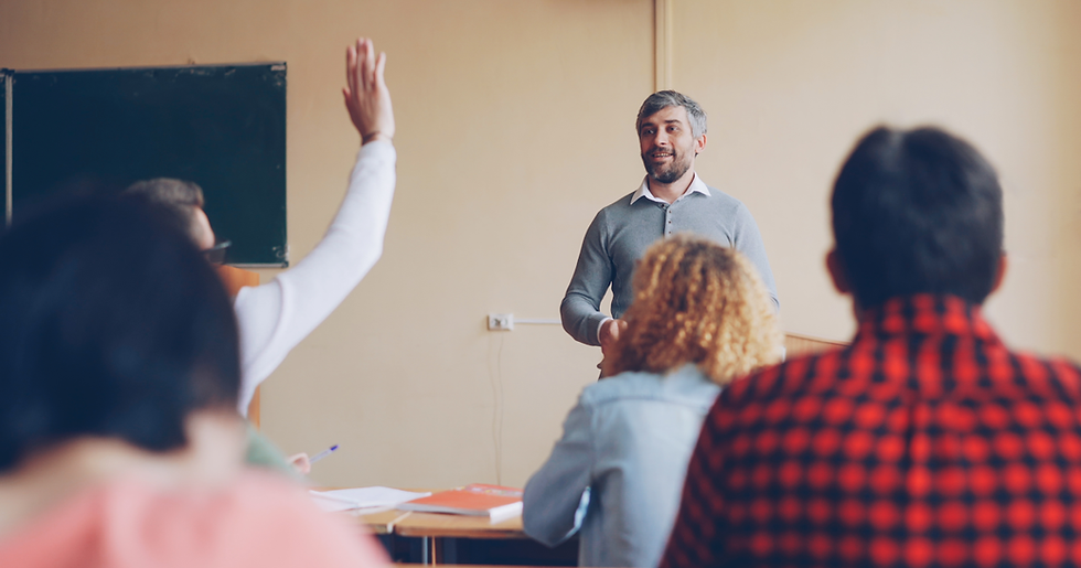 Student raising hand to ask question while teacher responds in Zoho CRM training classroom representing evaluation before enrollment
