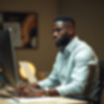 create an image of a black man at the desk on a computer working .jpg