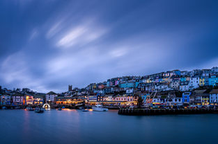 Blue hour long exposure of Brixham Harbour looking towards the town, with town lights and Christmas lights reflecting in calm, flattened water.
