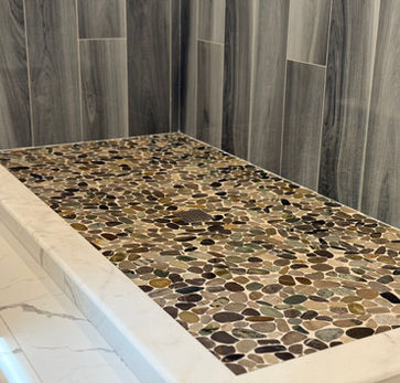 Pebble tile shower floor with gray wall tile