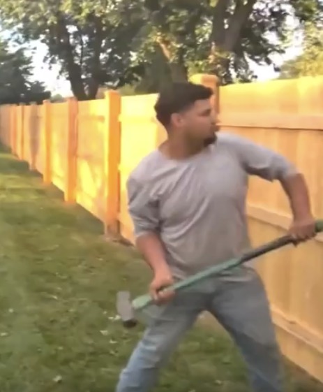 Worker dismantling a wooden fence during a payment dispute in Joliet, Illinois