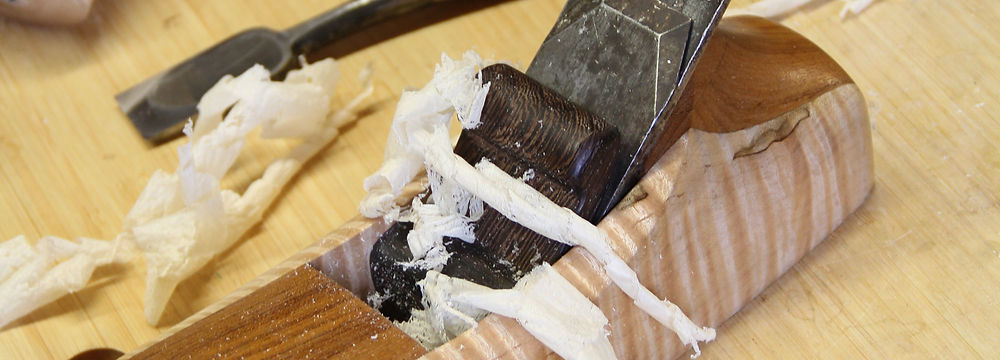 A wooden Krenov-style handplane on a workbench with some chisels and a mallet