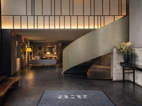 Lobby at Hotel AKA NoMad featuring a curved floating staircase and moody warm lighting