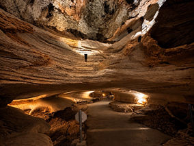 Illuminated cave passage inside Longhorn Cavern State Park with a paved walking path and limestone formations.
