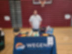 a male in front of a table at the Sandy High School Thrive at 25 event