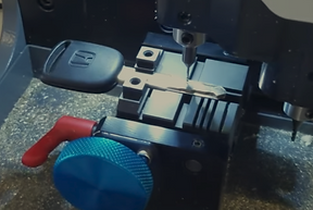 Picture of a car key being cut by cutting machine