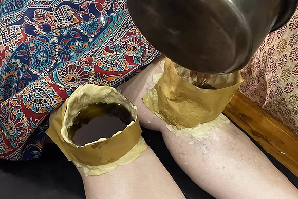 Warm oil therapy on the knees – Ayurvedic natural treatment for joint pain and mobility.