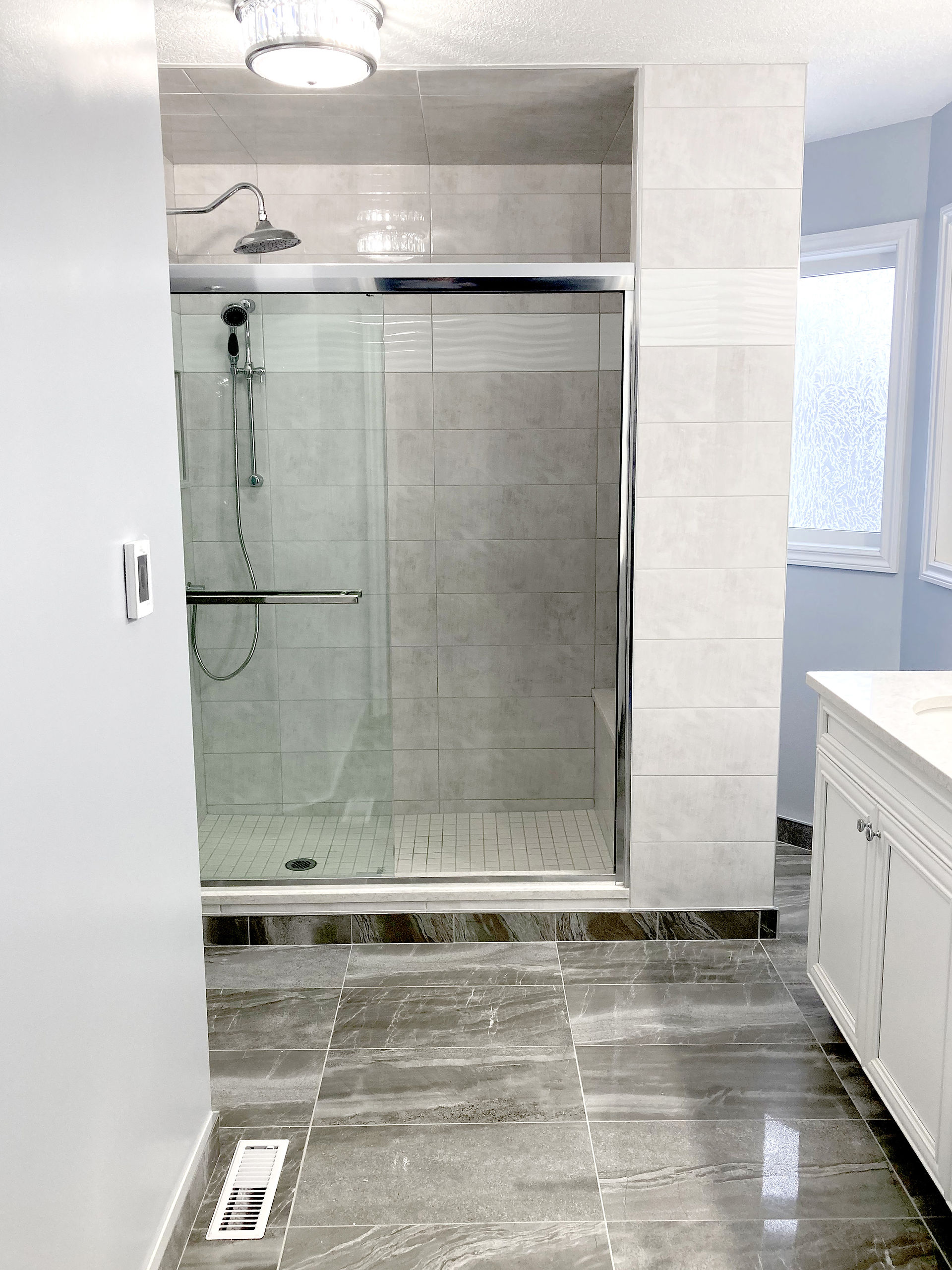 The existing bathtub and cabinets were removed. We framed for a larger walk in shower with new faucets, built-in seat, and a glass door.