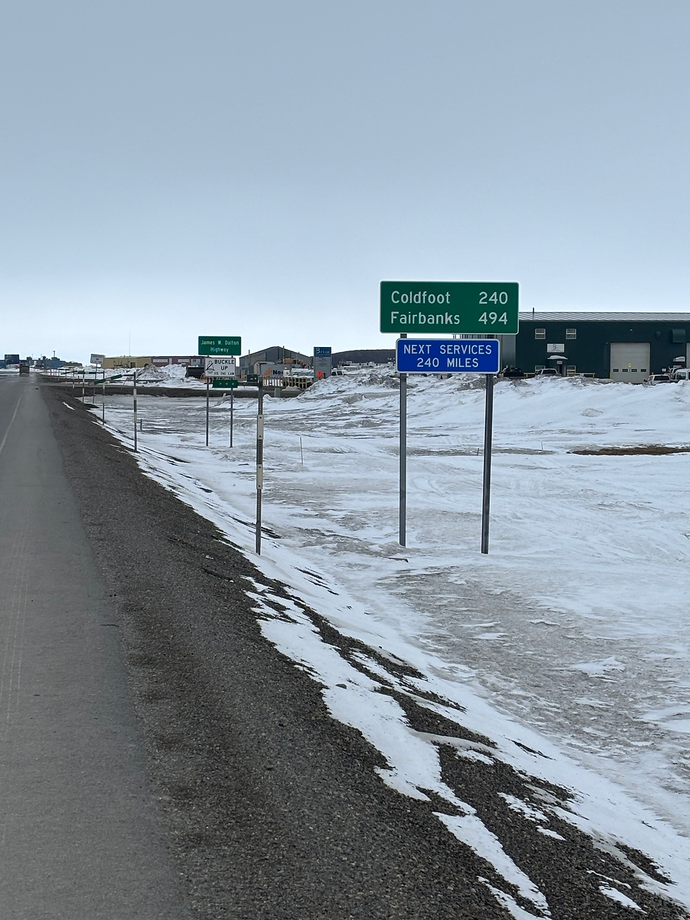 Snowy roadside with directional signs indicating distances to Coldfoot (240 miles) and Fairbanks (494 miles). Next services in 240 miles.