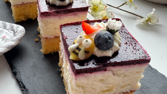 Heidelbeerschnitte mit Blüten auf schwarzer Schieferplatte und Deko