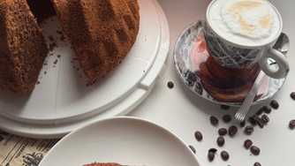 Schoko-Kaffee-Guglhupf mit 1 Tasse Kaffee, brennende Dekolichter, Kaffeebohnen, 1 Stück aufgeschnittener Guglhupf