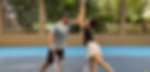 Couple high five at tennis court during tennis lesson