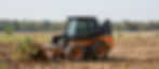 Skid steer performing tree and land clearing services.