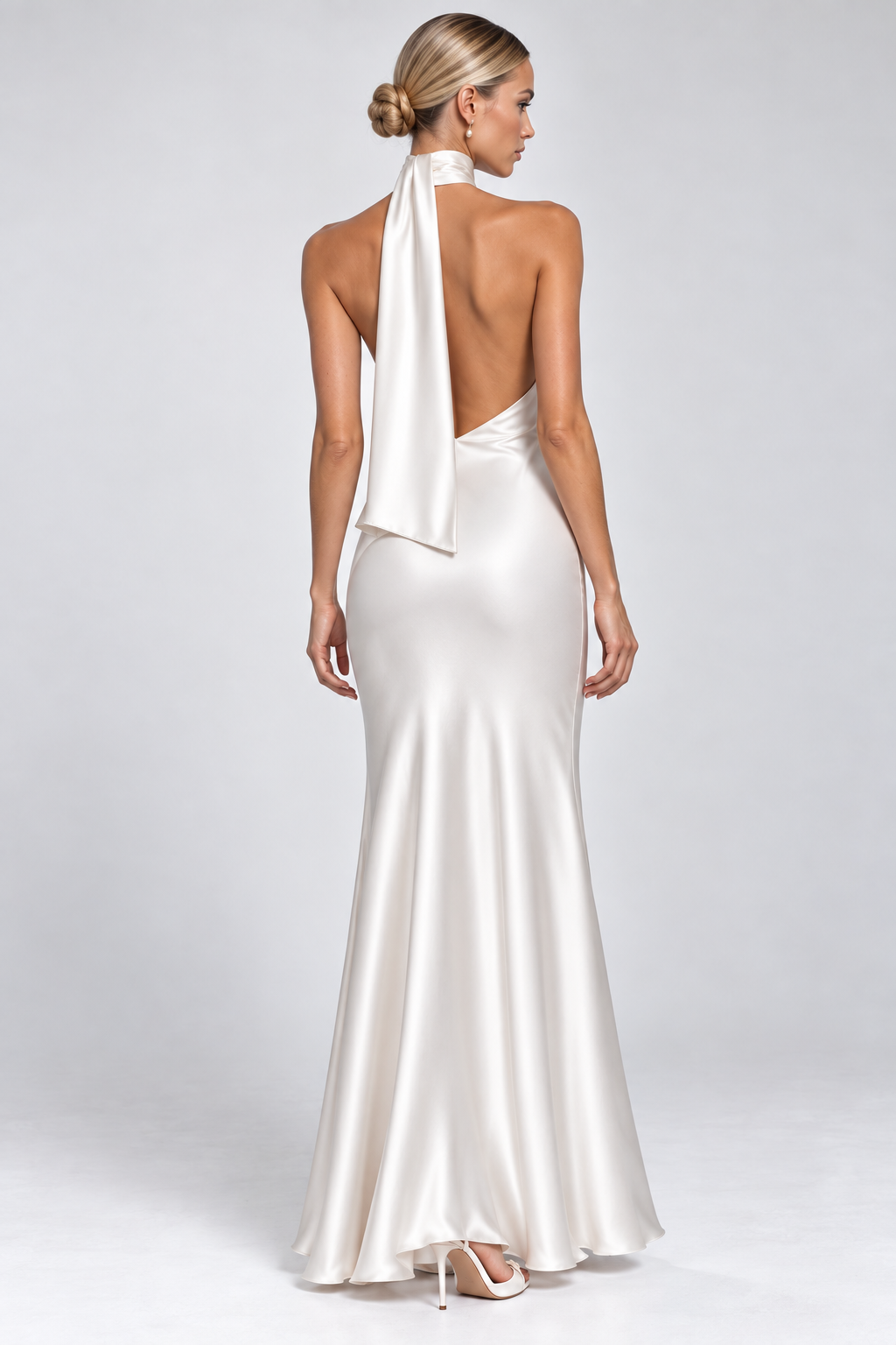 White satin halter neck maxi dress with asymmetric neckline, fitted silhouette and floor-length skirt.