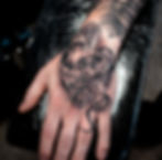 Realistic black and grey hand tattoo of a skull entwined by a snake, by Dagga