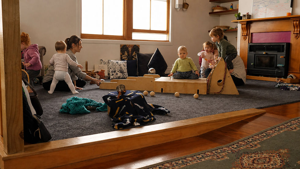 Children and teachers in the carpeted playroom with a wooden ramp at Little Geckos.