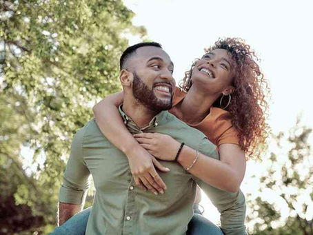 A professional photo of a couple smiling and embracing in a natural setting, symbolizing intimacy and well-being