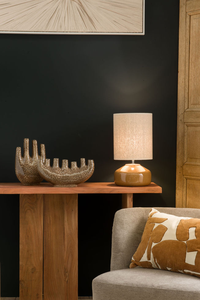 Lampe Domitille marron en céramique terre cuite avec abat-jour en coton beige sur une console en bois.