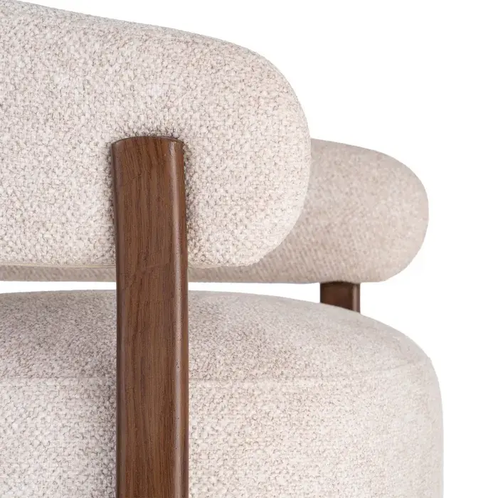 Fauteuil enveloppant en tissu beige texturé avec pieds en métal effet bois.