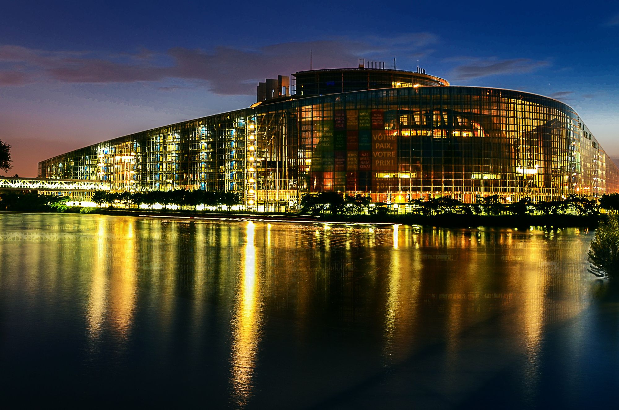 The European Parliament in Strasbourg at night, reflected in the water.