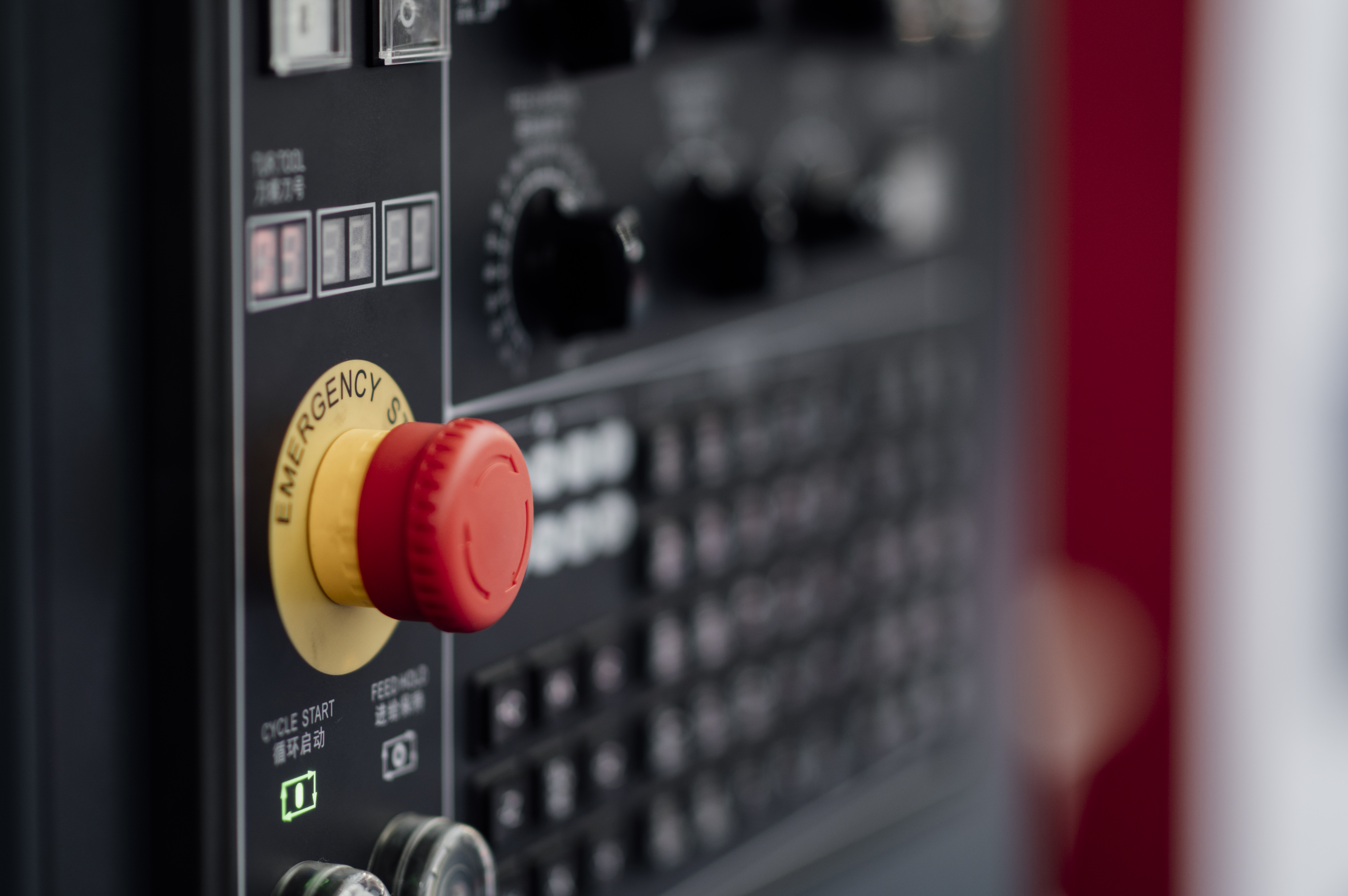 A red emergency stop button on an industrial control panel.