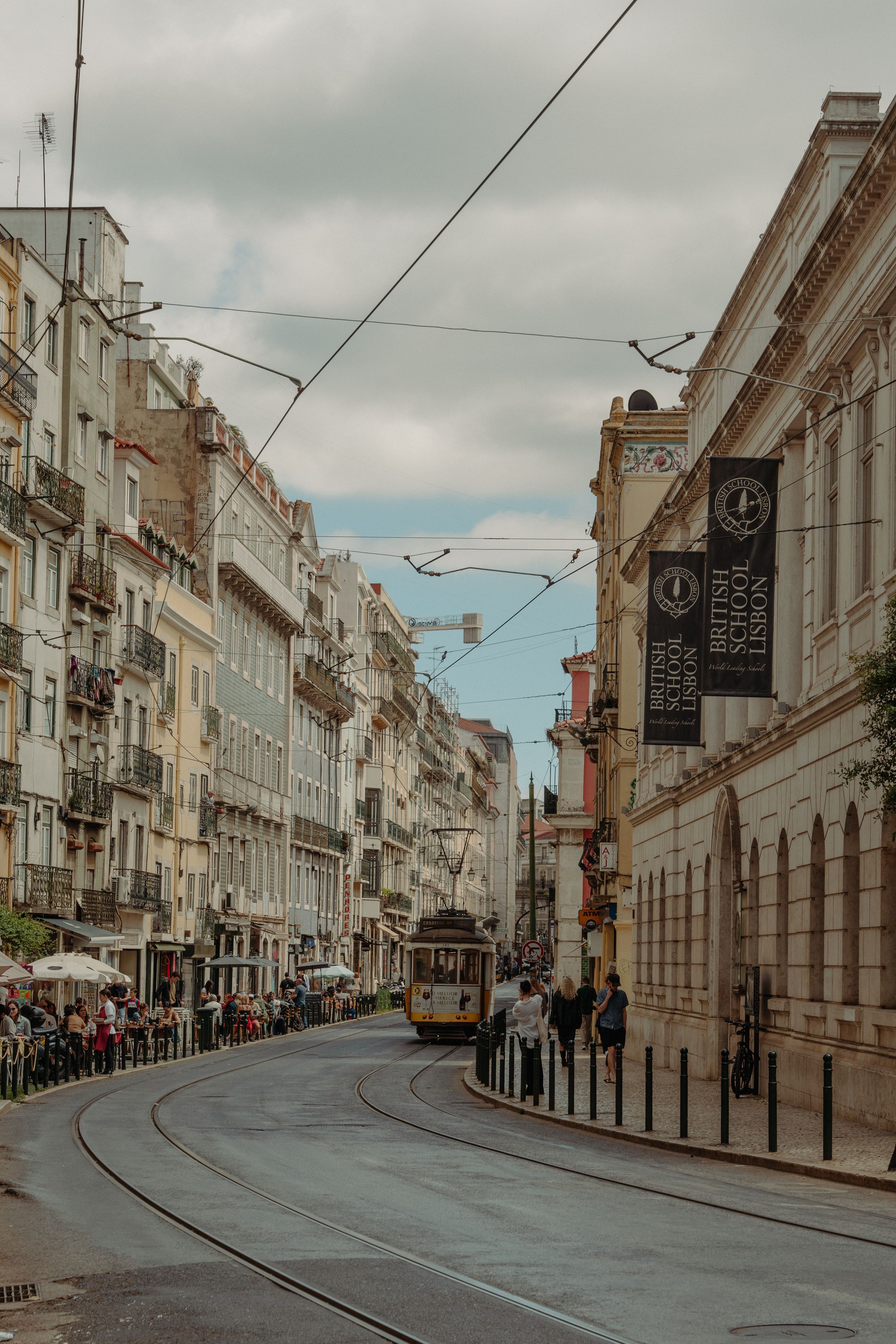 A classic Lisbon tram on a historic city street on an overcast day.