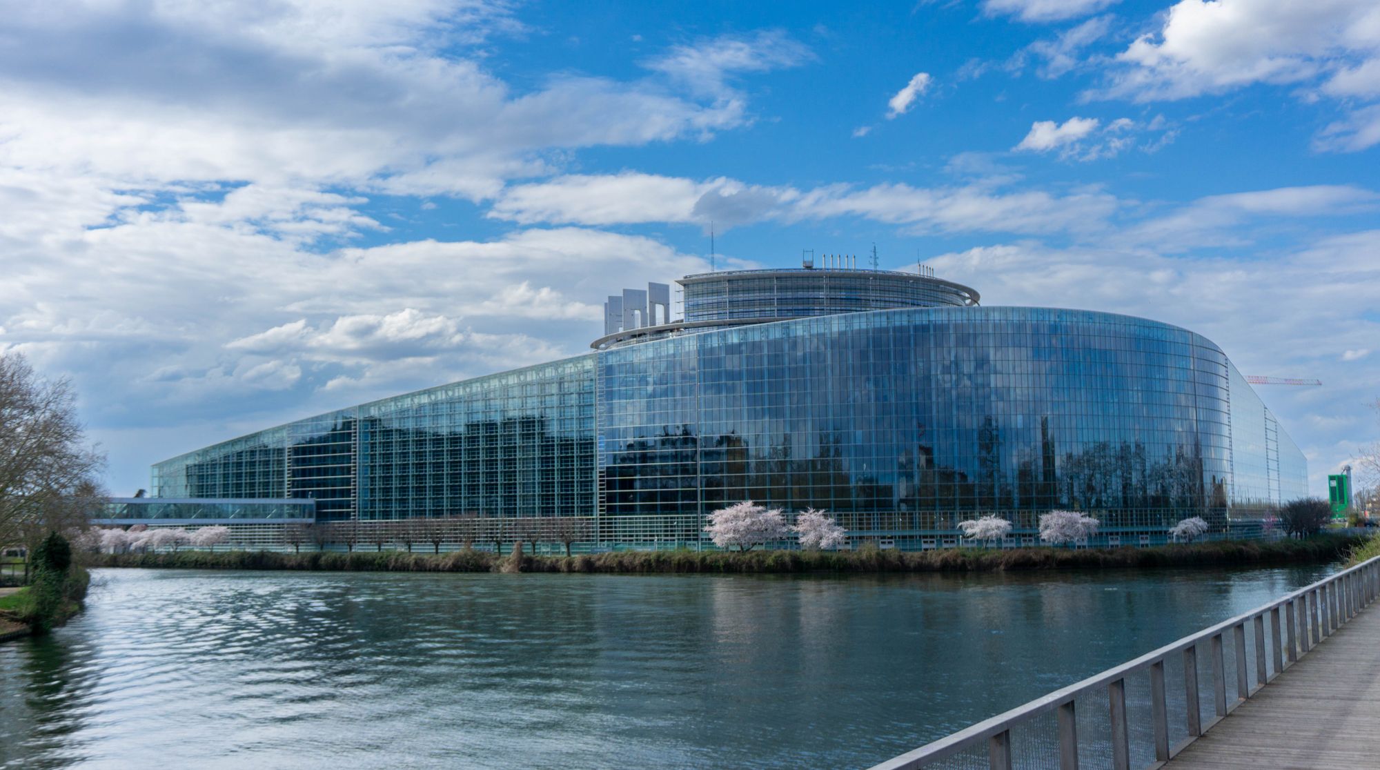 The European Parliament building in Strasbourg with its curved glass facade beside the river.