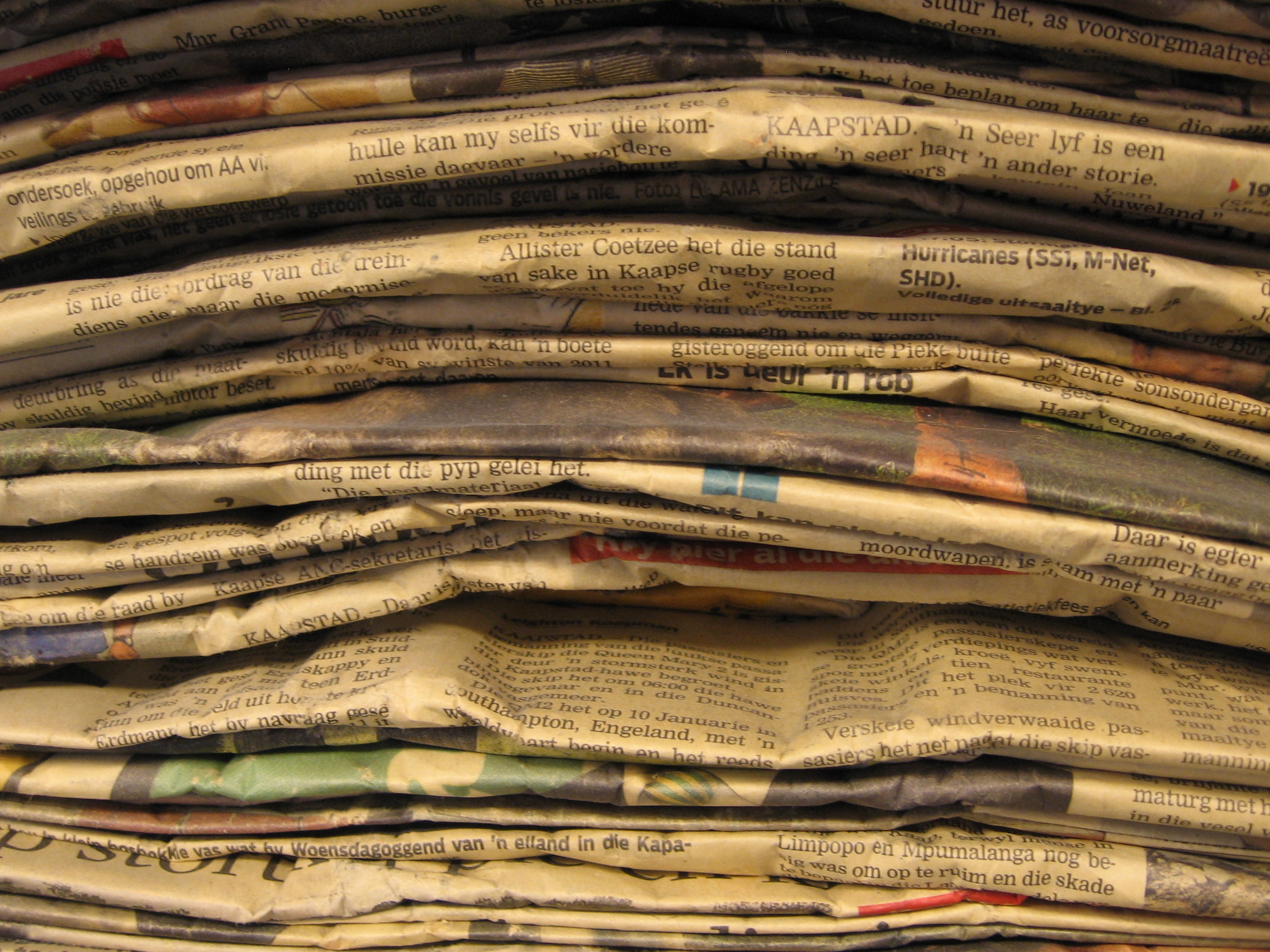 A tall stack of printed newspapers, banded and stored.
