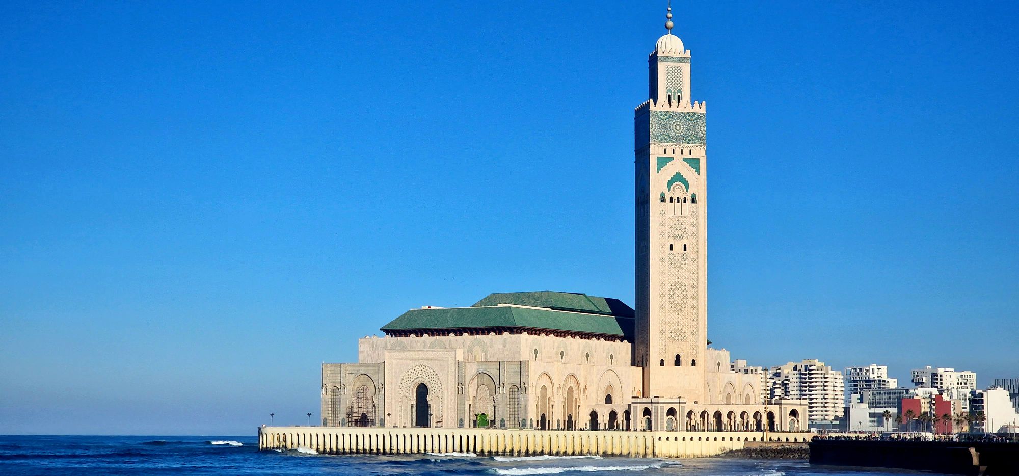 The Hassan II Mosque in Casablanca against a blue sky.