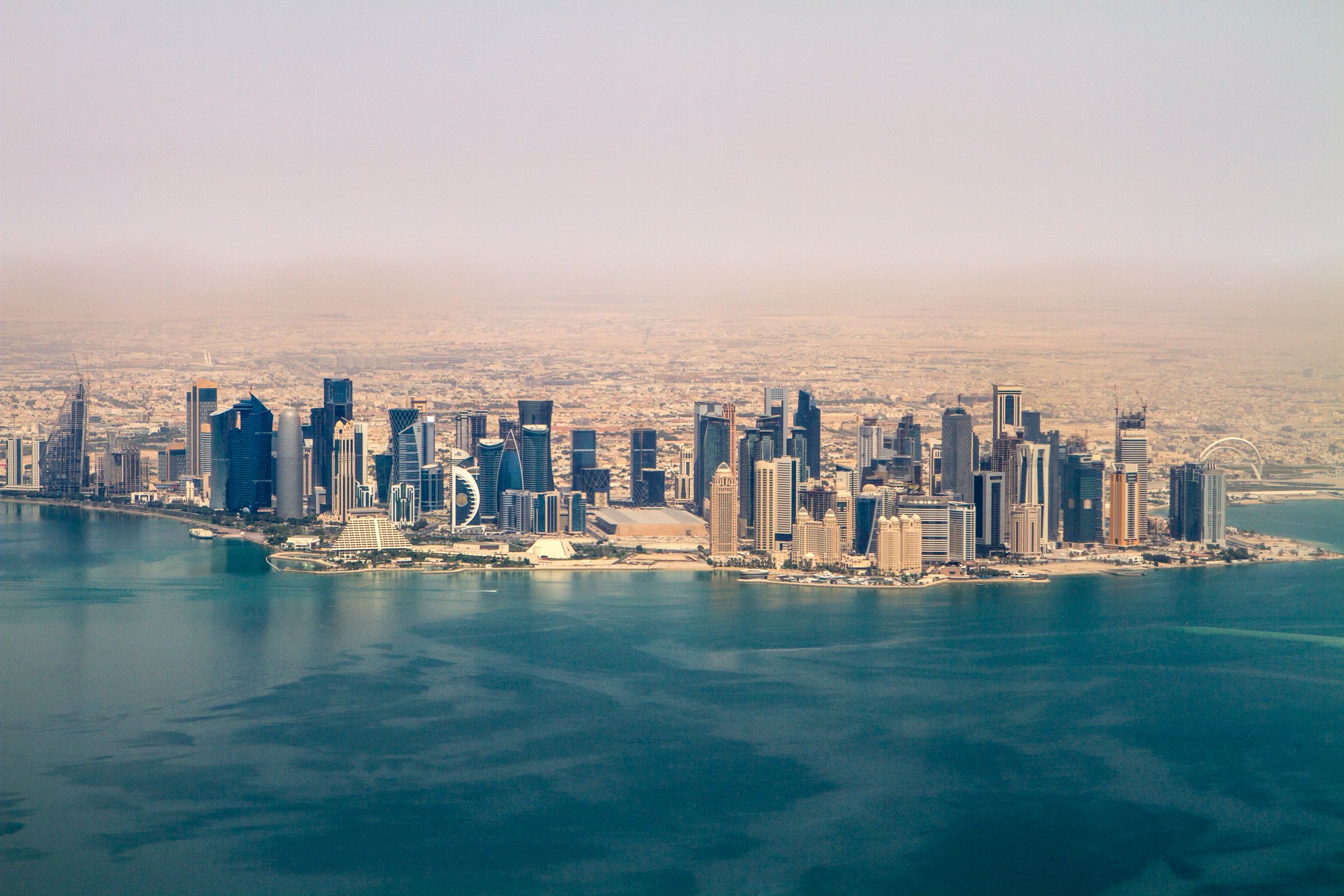 An aerial view of the Doha skyline under a clear sky.