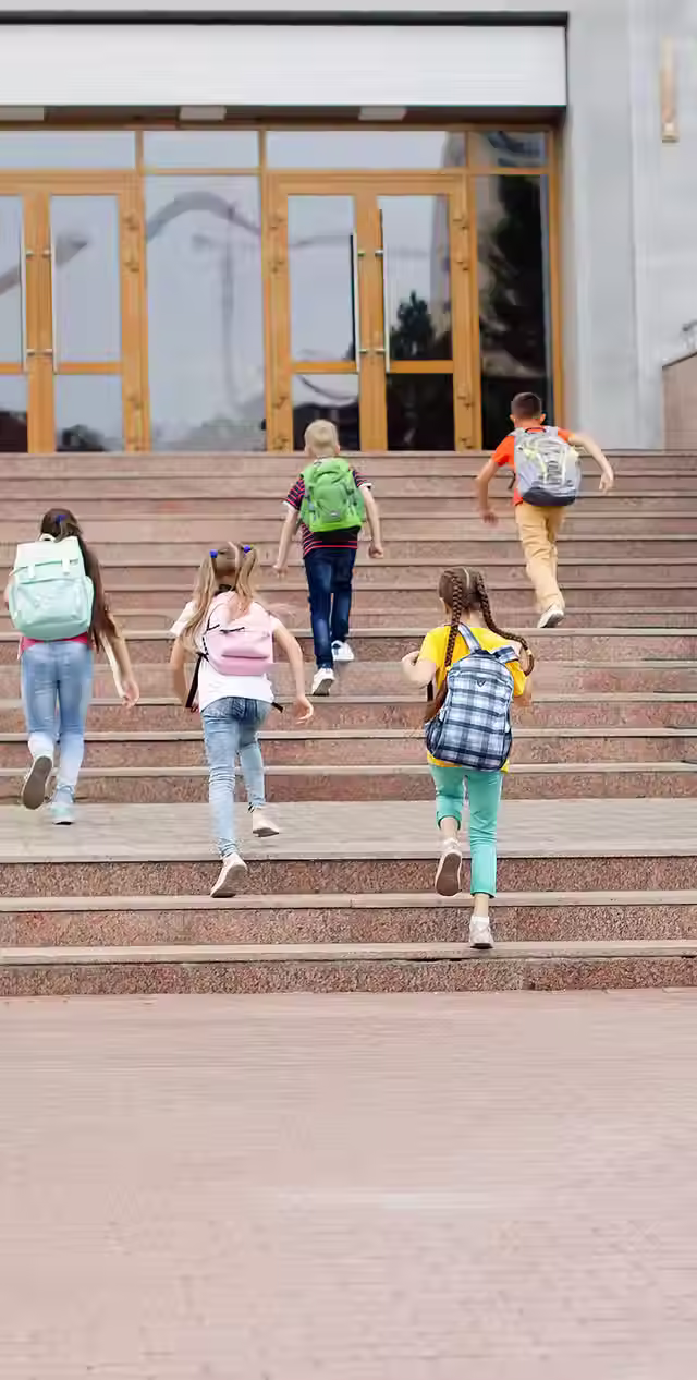 kids with backpacks walking up the stairs to school